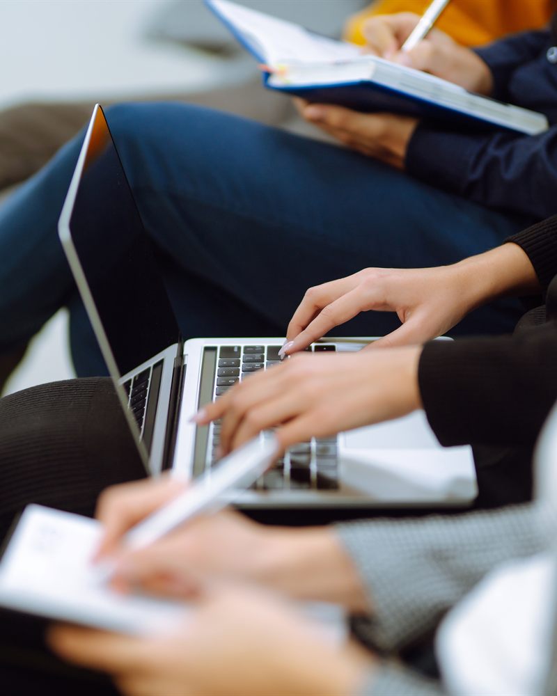 Varias personas siguiendo una sesión con computadoras portátiles y tomando notas.