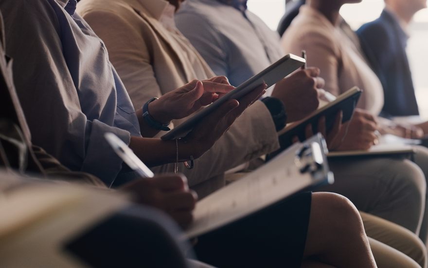 Asistentes a una sesión de formación tomando notas en tabletas y cuadernos.