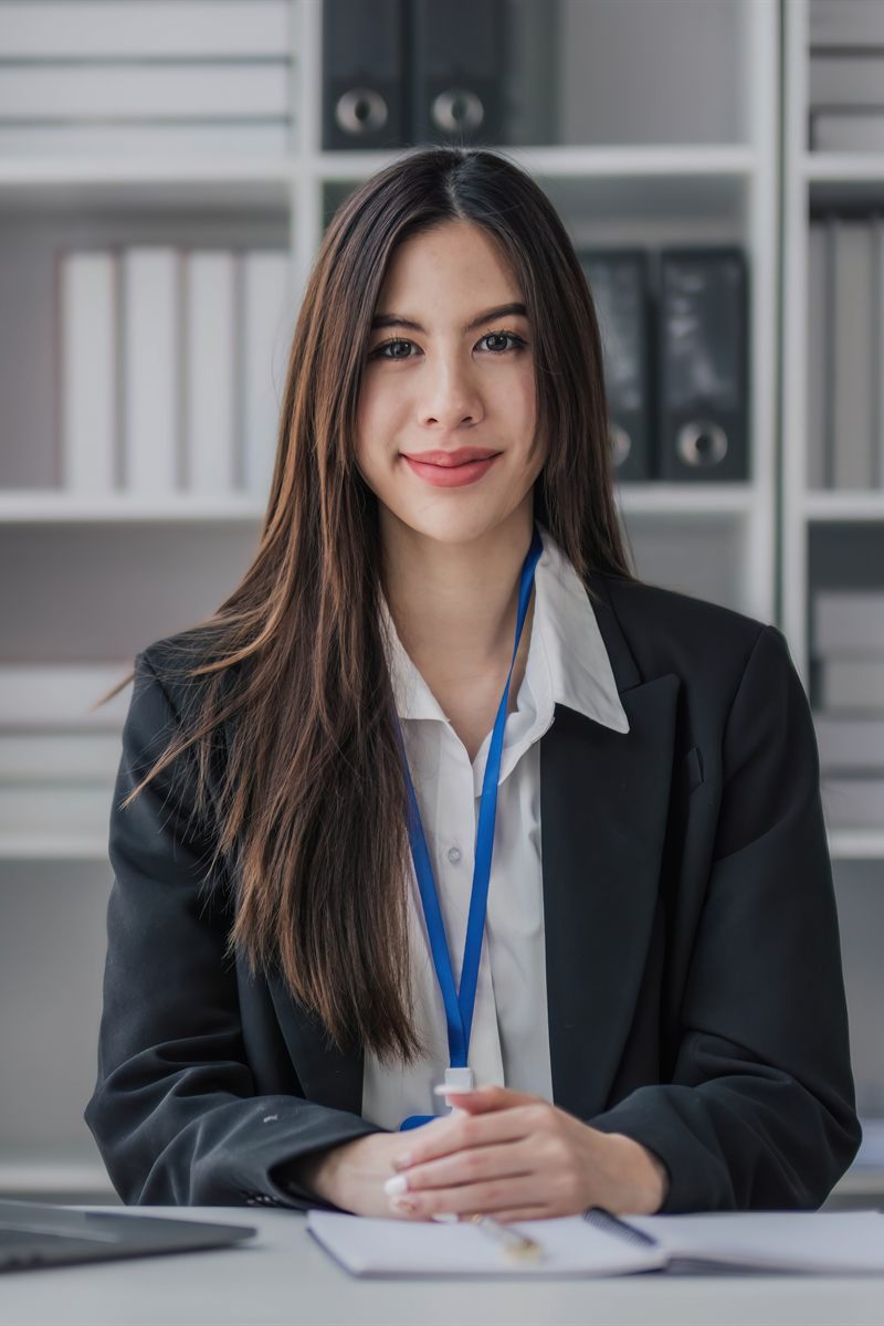 Profesional con credencial trabajando frente a una computadora portátil en una oficina.